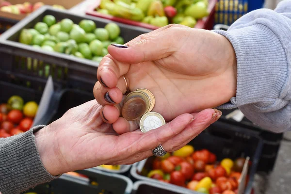 yaşlı bir kadın piyasa ürünleri satın alırken elleri