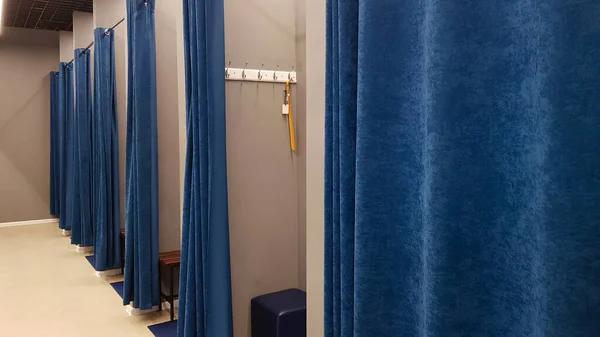 Butik iç mekan, alışveriş merkezindeki soyunma odası. Hiç kimse. Mavi perdeli, gri duvarlı ve büyük aynalı boş odalar. Bir giyim mağazasında insanların olmadığı soyunma odaları