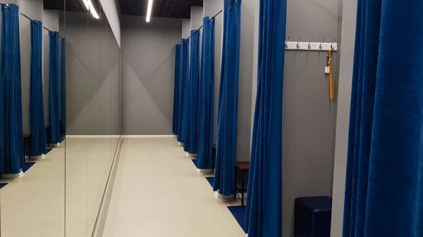 Butik iç mekan, alışveriş merkezindeki soyunma odası. Hiç kimse. Mavi perdeli, gri duvarlı ve büyük aynalı boş odalar. Bir giyim mağazasında insanların olmadığı soyunma odaları