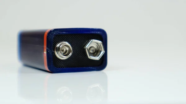 Una batería PP3 azul usada sobre un fondo blanco con reflexión. Batería principal para fuentes de alimentación personales. Primer plano de un conector de batería rayado y usado. — Foto de Stock