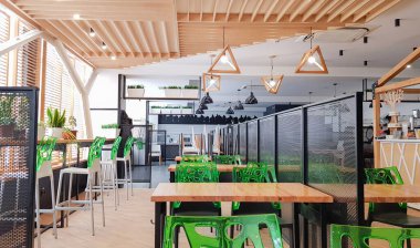 Geniş kafeterya, bir sürü ahşap masa ve yeşil sandalyeli yemek odası yok. İçi ahşap ve metal elementlerle dolu, beyaz duvarlarla. Pencerelerden doğal ışık alan modern toplumsal yemek alanları.