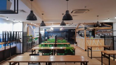 Kafeterya, ahşap masalı ve yeşil sandalyeli yemek odası yok. İçi ahşap ve metal elementlerle dolu. Pencere ışıklandırmalı modern yemek alanları. Ukrayna, Kiev - 19 Şubat 2021.