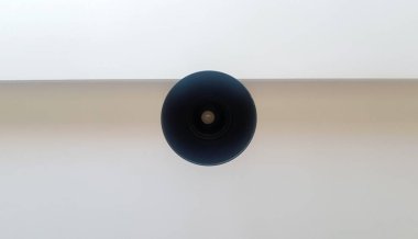 Tavandan sarkan siyah yuvarlak avize ya da beyaz lamba. Ampulün alt görüntüsü. Tavanda mimari dekorasyon, avizenin etrafında asılı. Minimalizm