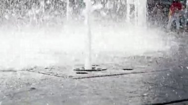 Meydanda bir yaya çeşmesi deresi, yakın plan. Şehir merkezinde yere gömülü bir gayzer başlığından sokaktaki bir çeşmeden su fışkırıyor.