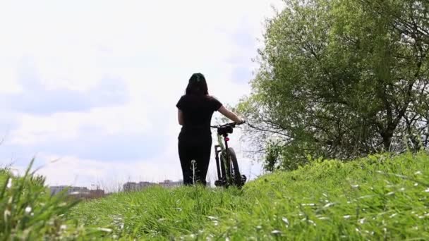 年轻妇女骑自行车旅行 冒险和旅行的概念 一个健康的游客正在骑自行车散步 欣赏大自然和阳光 那女孩把自行车卷起来了 体育妇女的生活方式 — 图库视频影像