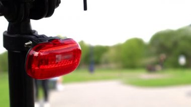 Gündüz vakti bir bisiklete yakın planda yanıp sönen LED kırmızı stop lambası monte edildi. Kırmızı çerçeve uyarı ışığıyla motorun arkası.