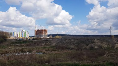 Tarlanın ve güneşli bir günde başlayan çok katlı yüksek binaların inşaatının bir fotoğrafı. Yeni bir yerleşim alanının inşaatı