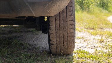 Toprak yolda beyaz, modern bir arabanın yolcu tarafı, tampon ve tekerleğin dikiz açısı. Çok düşük bir plan.