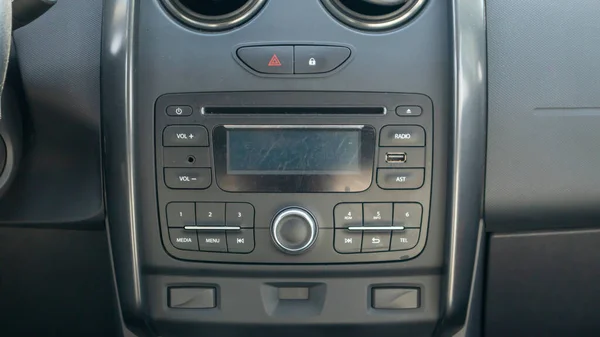 Established multimedia in the car. Close-up of the head unit and radio receiver with display inside the car. Dust and scratches are visible on the device screen. Multimedia system
