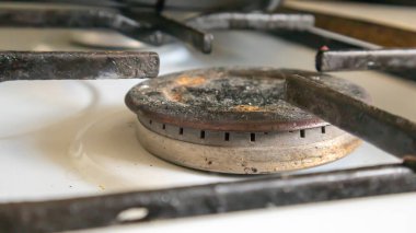 Mutfakta sebze yağı lekeleri ve yanmış yiyecek artıklarıyla pişirmek için kirli gaz ocağı var. Yakın plan. Seçici odaklanma. Mutfakta yağ kaplı benzin deposu var.