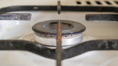 Mutfakta sebze yağı lekeleri ve yanmış yiyecek artıklarıyla pişirmek için kirli gaz ocağı var. Yakın plan. Seçici odaklanma. Mutfakta yağ kaplı benzin deposu var.