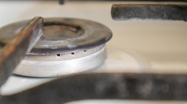 Mutfakta sebze yağı lekeleri ve yanmış yiyecek artıklarıyla pişirmek için kirli gaz ocağı var. Yakın plan. Seçici odaklanma. Mutfakta yağ kaplı benzin deposu var.