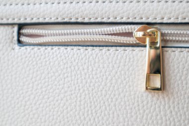 Doğal ya da yapay deri dokusu. Bir parça bej ya da fermuarlı ve dikişli toz torbası. Fermuar ya da toka tasarım elemanı. Yılanlı sığır derisi. Makro fotoğraf, seçici odak