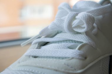 Beyaz bağcıklı spor ayakkabılar. Beyaz bağcıklar yakından bağlanmış. Arka plan bulanık. Spor konsepti. Ayakkabı için metal perçin. Detay olarak ya da element olarak. Şık ve şık ayakkabılar.