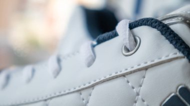 Beyaz bağcıklı spor ayakkabılar. Beyaz bağcıklar yakından bağlanmış. Arka plan bulanık. Spor konsepti. Ayakkabı için metal perçin. Detay olarak ya da element olarak. Şık ve şık ayakkabılar.