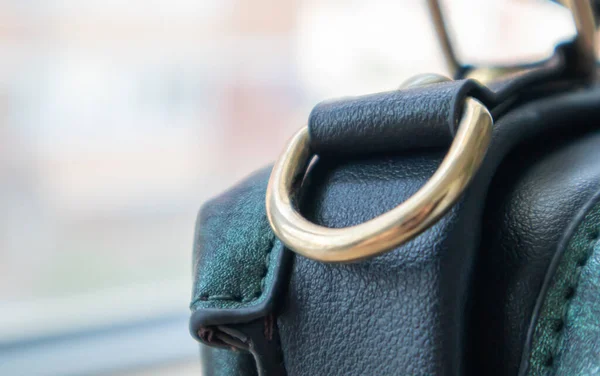 Metal gold loop oval ring attached to a leather bag. Selective focus. Part for a secure connection between two objects. Sewing accessories in the form of a ring for sewing bags, glossy