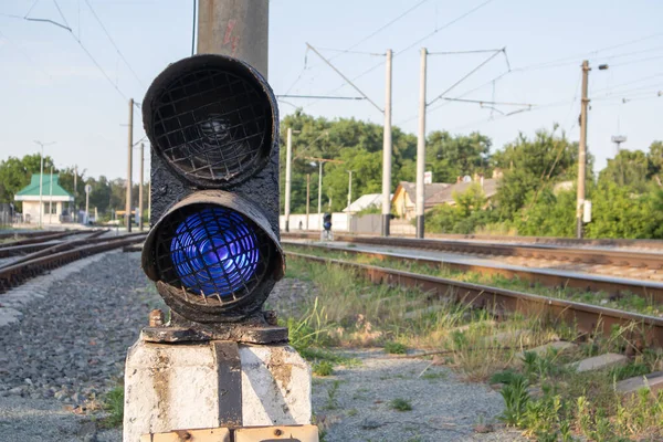 Railroad signal with blue light with a railroad junction. Train blue traffic light prohibiting traffic. Railway junction. Heavy industry. Railways. The traffic light on the railway is lit in blue