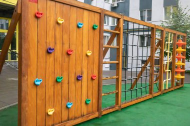 Yağmurlu bir yaz gününde ağaçtan ve plastikten yapılmış modern ve büyük bir oyun alanı olan yüksek binalardan oluşan bir avlu. Açık hava çocuk parkı. Çocuk oyunları ve spor için bir yer.