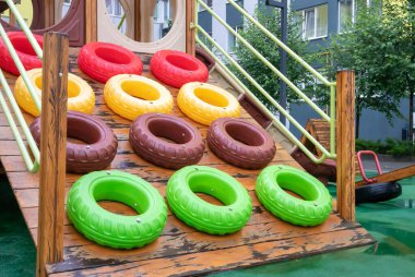 Yağmurlu bir yaz gününde ağaçtan ve plastikten yapılmış modern ve büyük bir oyun alanı olan yüksek binalardan oluşan bir avlu. Açık hava çocuk parkı. Çocuk oyunları ve spor için bir yer.