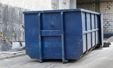 İnşaat alanındaki açık hava çöpleri için metal dayanıklı mavi endüstriyel çöp kutusu. Ev ya da endüstriyel atıklar için büyük bir çöp kutusu. Bir çöp yığını.
