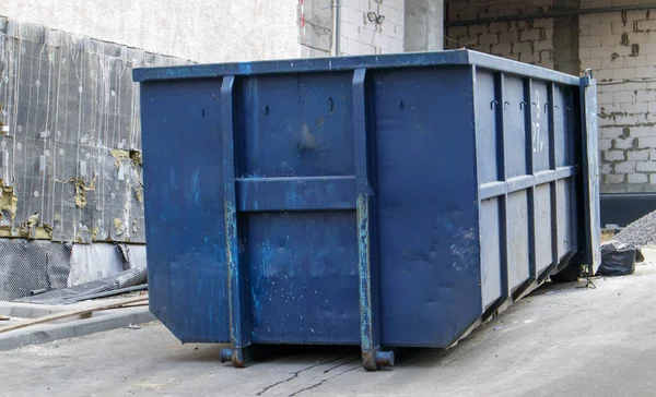 İnşaat alanındaki açık hava çöpleri için metal dayanıklı mavi endüstriyel çöp kutusu. Ev ya da endüstriyel atıklar için büyük bir çöp kutusu. Bir çöp yığını.