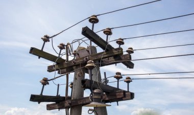 Yüksek voltajlı kabloları olan tahta elektrik direği. Mavi gökyüzüne karşı sütun. Mavi gökyüzüne karşı eski ahşap telefon direği