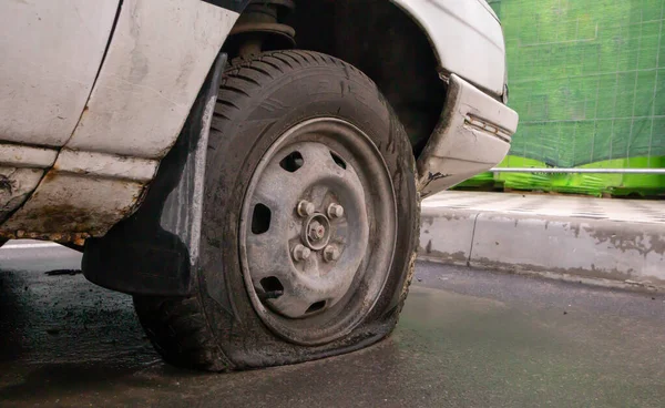 Abandoned old broken car with flat wheels. A tire with a flat tire. The concept of accident, breakdown, repair, insurance. A flat tire on a car wheel