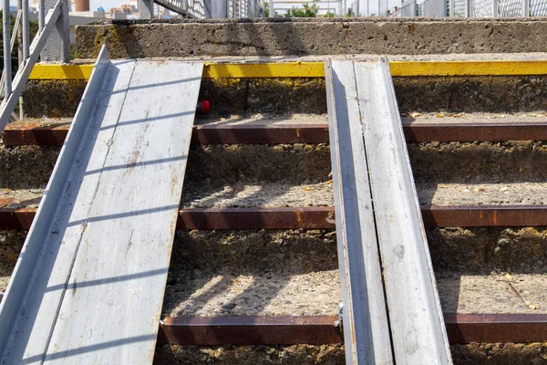 The staircase of the pedestrian crossing with traces of destruction. Two wheelchair rails. Metal railings for bicycles, wheelchairs and strollers with children. Special equipment on the stairs