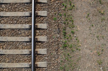 Demiryolu manzaralı, düz yatıyordu. Tren raylarının bir parçası. Bir insansız hava aracından demiryolu görüntüsü. Metin için arkaplanda boşluk var. Parlak demir raylar ve beton uykucular