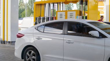 Beyaz araba yakıt ikmali yapıyor. Benzin istasyonuna park edilmiş bir arabayı doldurmak. Benzin pompalı araçlar. Petrol ve gaz enerjisi. Ukrayna, Kiev - 15 Ağustos 2021