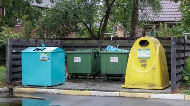 Bir yerleşim yerinin avlusunda atık ayıklamak için dört plastik ve metal çöp kovası. Konut binasının avlusundaki çöp tenekeleri. Ukrayna, Kiev - 29 Ağustos 2021