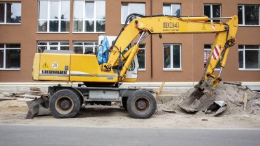 İnşaat halindeki bir binanın arka planında sarı renkli mobil vinç yükleyicisi var. Uluslararası donanım üreticisi. Kazı makinesi toprak işlerinde kullanılır. Ukrayna, Kiev - 11 Eylül 2021