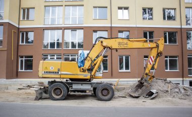 İnşaat halindeki bir binanın arka planında sarı renkli mobil vinç yükleyicisi var. Uluslararası donanım üreticisi. Kazı makinesi toprak işlerinde kullanılır. Ukrayna, Kiev - 11 Eylül 2021