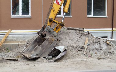 İnşaat halindeki bir binanın arka planında sarı renkli mobil vinç yükleyicisi var. Alman-İsviçreli uluslararası ekipman üreticisi. Kazı makinesi toprak işlerinde kullanılır.
