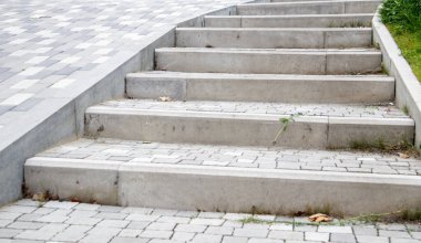 Kaldırım levhaları ve kaldırımlar. Gri kaldırım levhalarından yapılmış gri basamaklar birbirine eşit, tutarlı ve sıkıca dizilir. Asfalt basamaklar gri arkaplan