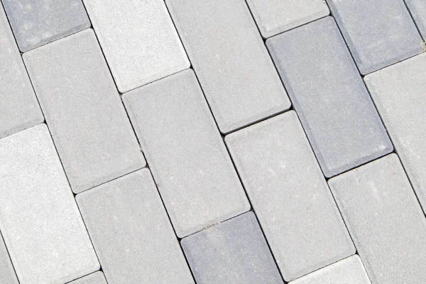 Concrete or paved newly laid gray paving slabs or stones for floors or walkways. Concrete paving slabs in the backyard or road paving. Garden brick path in the courtyard on a sandy foundation