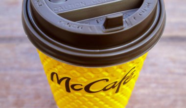 McDonald 's' ın bulanık şehrine karşı masada McCafe için kahve ve kağıt sarısı cam bardak. Fast food işi geçmişi. Fast food restoran menüsü. Ukrayna, Kiev - 13 Eylül 2021