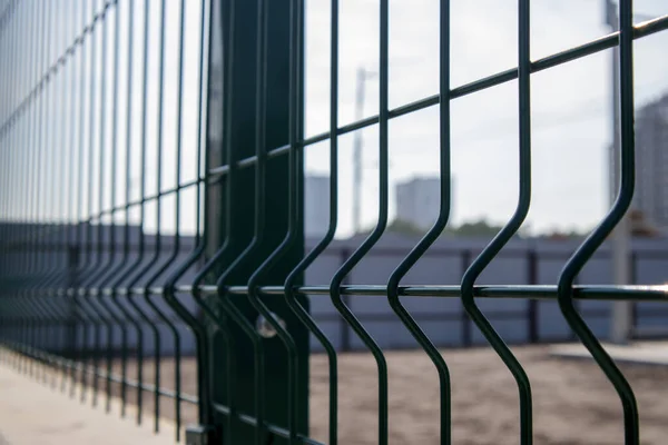 Steel lattice green fence with wire. Fencing. Grid industrial wire fence panels, pvc metal. Installation of sectional fencing. Welded mesh fence. Installation of a grid for fencing the territory