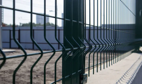 Steel lattice green fence with wire. Fencing. Grid industrial wire fence panels, pvc metal. Installation of sectional fencing. Welded mesh fence. Installation of a grid for fencing the territory