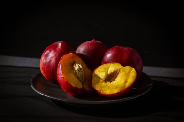 Sade arkaplanda gri bir tabakta parlak renkli nektarinler. 