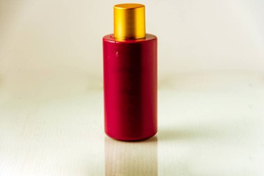 Arka planda küçük bir su damlası olan kırmızı bir şişenin stüdyo görüntüsü. Parfüm veya kozmetik paketi kavramı