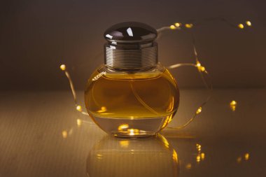 Parfüm şişesinin stüdyo fotoğrafı arka planda küçük ışık telleriyle.