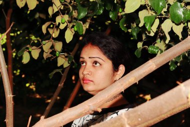 Hindistan 'ın bahçesindeki meyvelere bakarken güzel ve çekici yüzlü Hintli genç bayan poz veriyor.