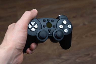 Adamın biri elinde video oyunu konsolundan kablosuz joystick tutuyor.