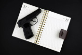 nabitá traumatická pistole leží na otevřeném zápisníku na černém pozadí
