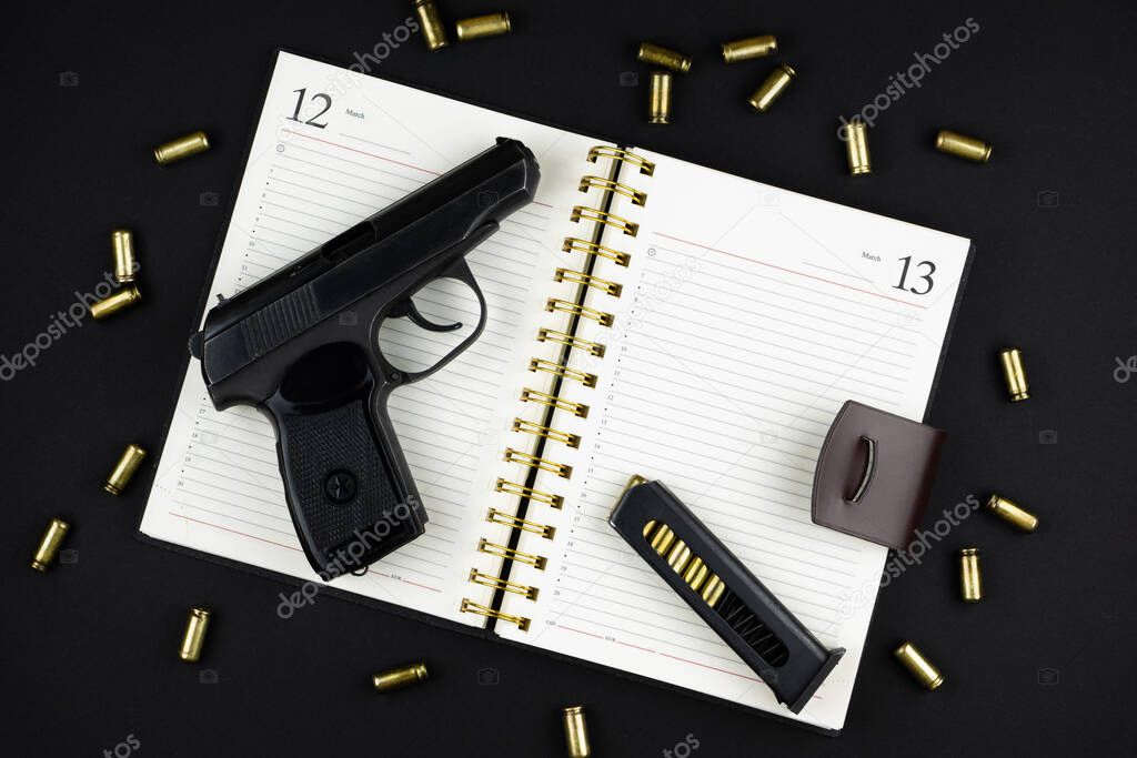 a traumatic pistol and ammunition are lying on an open notebook on a black background