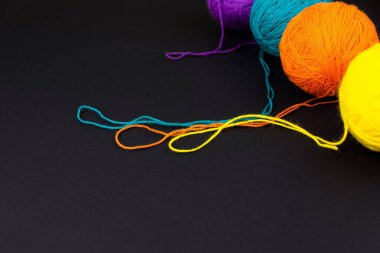 Siyah arka planda dört yuvarlak yün yumağı.