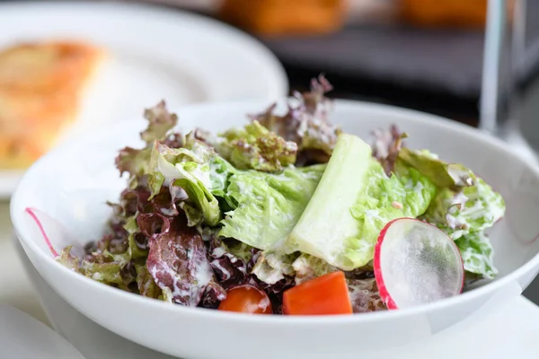 Yeşil salatayı beyaz tabakta karıştır..