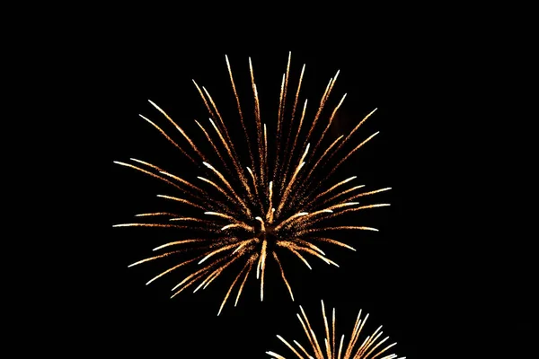 Yakın çekim havai fişekler gökyüzünde patlıyor. Siyah bir arkaplanda hareket bulanıklığı var..