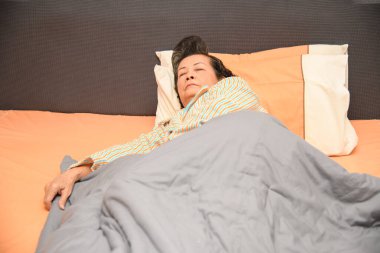 Yaşlı bir kadın yatak odasında yatağında uyuyor..